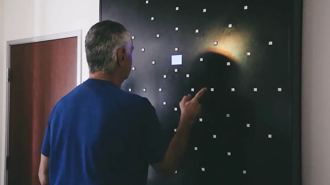 A hand striking a lit square on the DynaVision board during an assessment